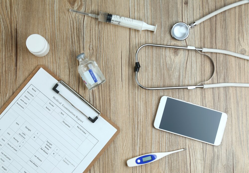 top view of medical examination report,cellphone,and medical equipments on wooden desk
