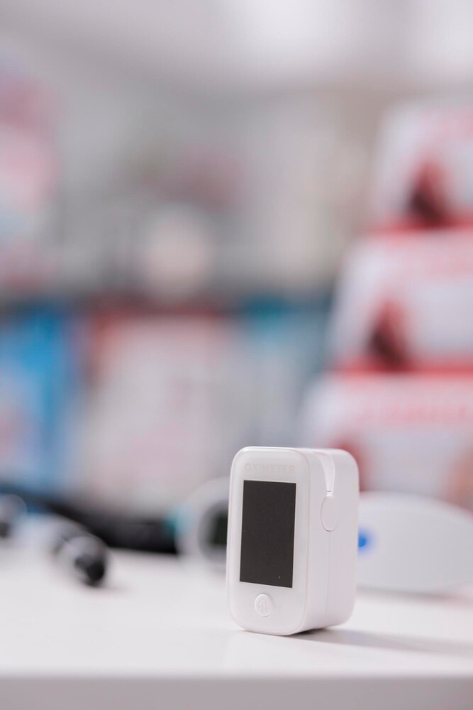 Medical oximeter standing on table in empty pharmacy ready to be used by customer, digital device to measure oxygen saturation. Drugstore filled with drugs, vitamins and pharmaceutical products